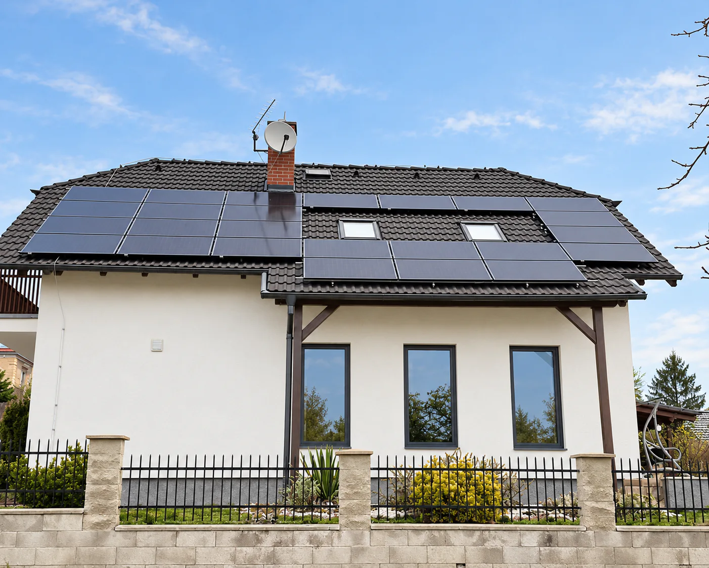 Fotovoltaické panely na střeše rodinného domu s bílou fasádou a antracitovými okny pod modrou oblohou; fotografie upravená pomocí AI.